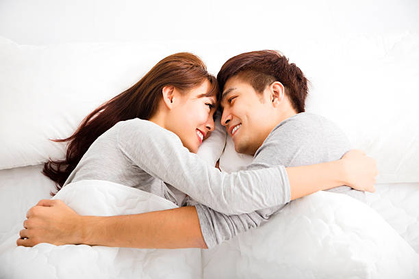 happy young lovely couple lying in a bed with comfortable duvet