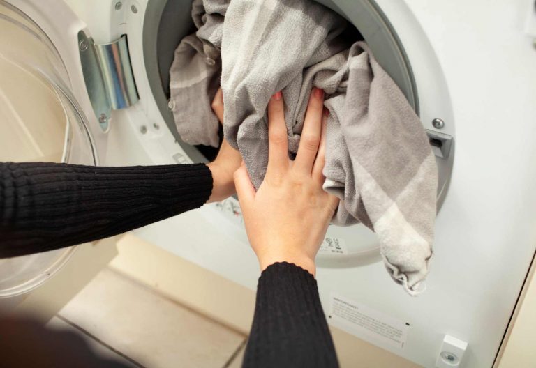 placing bed sheets into a washing machine, ensuring cleanliness and elimination of bed bugs