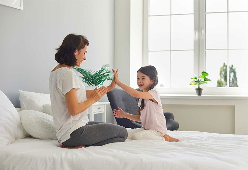 A mother and daughter share a playful moment, building good habits for restful nights.