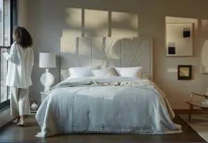 A beautifully made bed featuring the Vispring Luxury Beds, crafted with natural materials and showcasing expert craftsmanship for a truly luxurious sleep experience. The bed is set in a stylish room with sunlight streaming in, highlighting the high-quality bedding and elegant design.