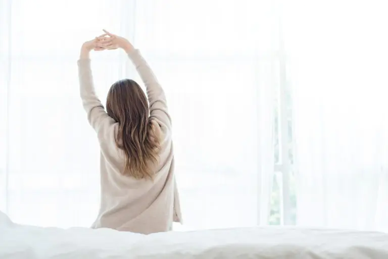 Back view of happy beautiful young asian woman waking up in morning