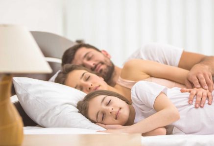 a family sleeping in a bed with the most comfortable pillow