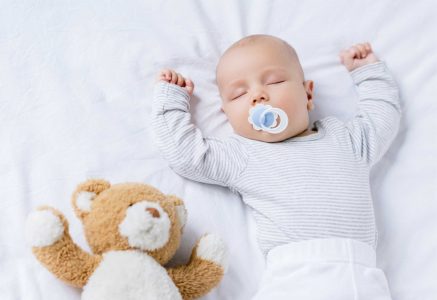 a baby sleeping with brown teddy bear describing when you use a good pillow
