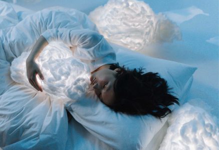 a girl sleeping in white bed with comfortable pillow