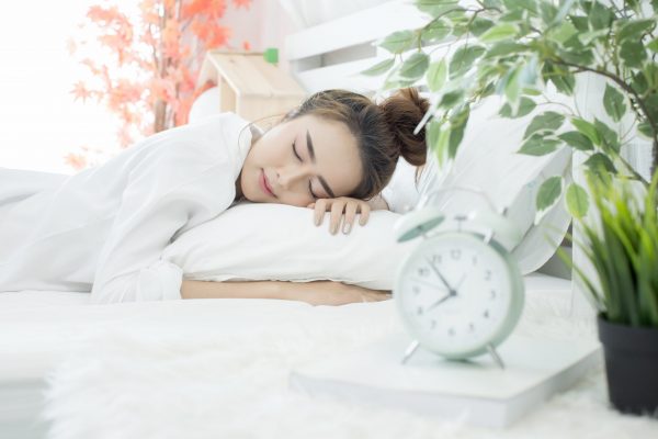 woman asleep in bed while her alarm shows the early time at home in bedroom